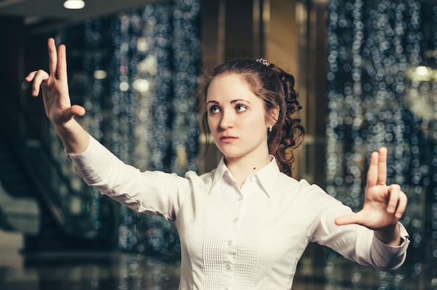 Chica joven que trabaja con un panel táctil virtual en la pantalla. Mujer de negocios interactúa con la interfaz holográfica en el cristal invisible.