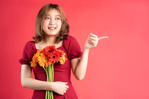 Chica joven con ramo de gerberas con expresión alegre en rosa