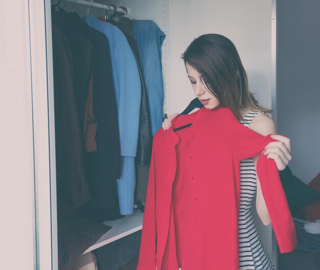 Chica joven rednead eligiendo una ropa en el armario.