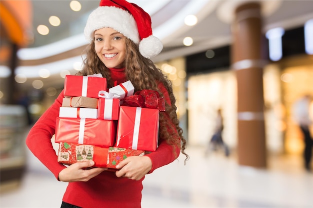 Chica joven con regalos de navidad en el fondo borroso del centro comercial