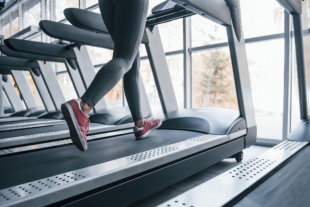 Chica joven en ropa deportiva corriendo en cinta en el gimnasio.