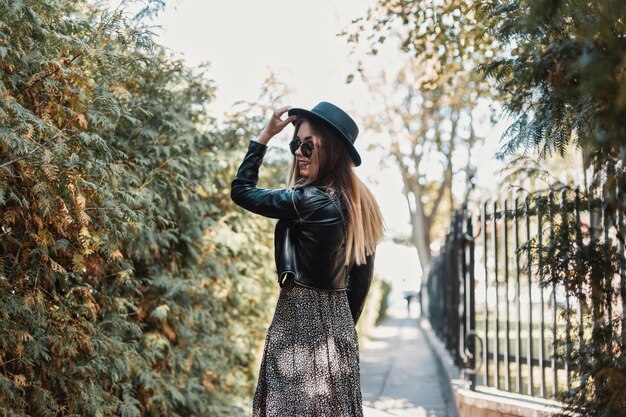 Chica joven en ropa de moda con sombrero camina por la calle en un día de otoño