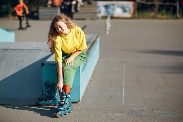 Chica joven en ropa verde y amarilla en patines.