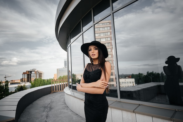 Foto chica joven y sexy elegante posando delante de un centro de negocios en negro. moda y estilo