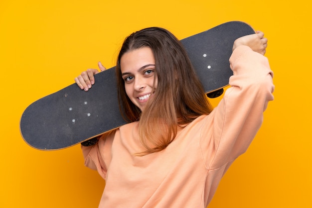 Chica joven skater sobre amarillo aislado