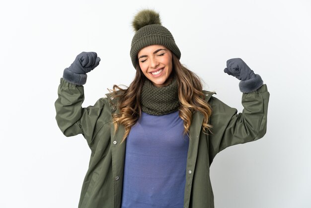 Chica joven con sombrero de invierno aislado sobre fondo blanco haciendo gesto fuerte