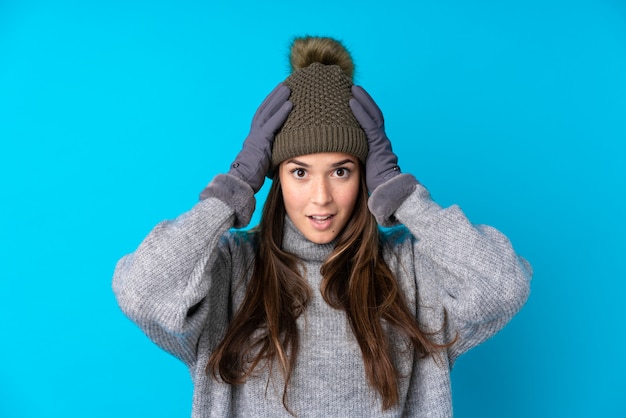 Chica joven con sombrero de invierno sobre pared aislada