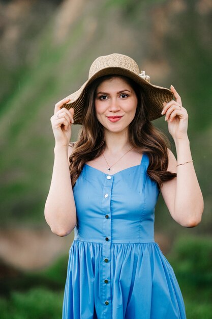 Chica joven con un sombrero de paja con ala grande en laderas verdes de la montaña