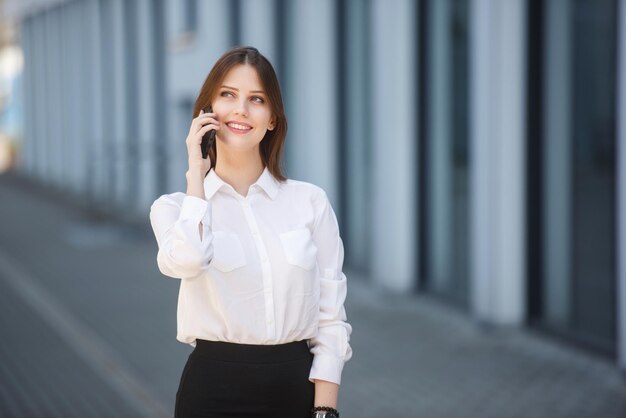 Chica joven sonriente que habla en el teléfono móvil