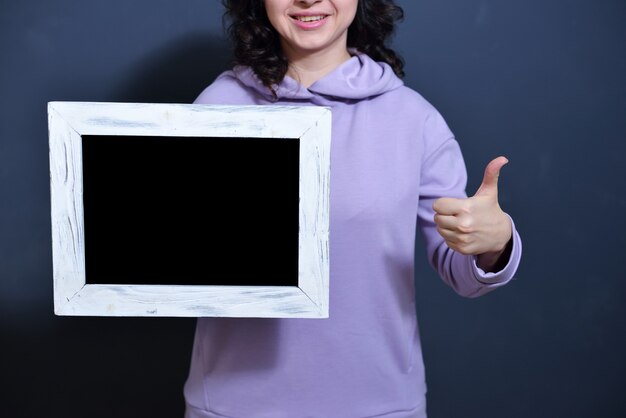 Chica joven sosteniendo un marco con metosma para la prueba. concepto de ventas y viernes negro después de la pandemia.