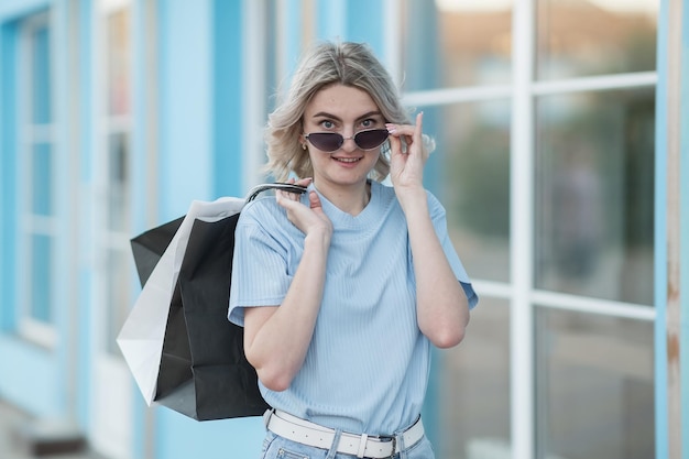 Foto una chica joven con un suéter azul y gafas al lado de la tienda al aire libre en verano