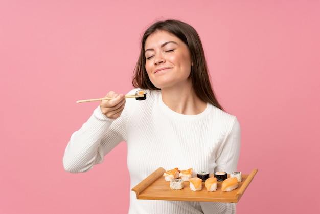 Chica joven con sushi sobre rosa aislado