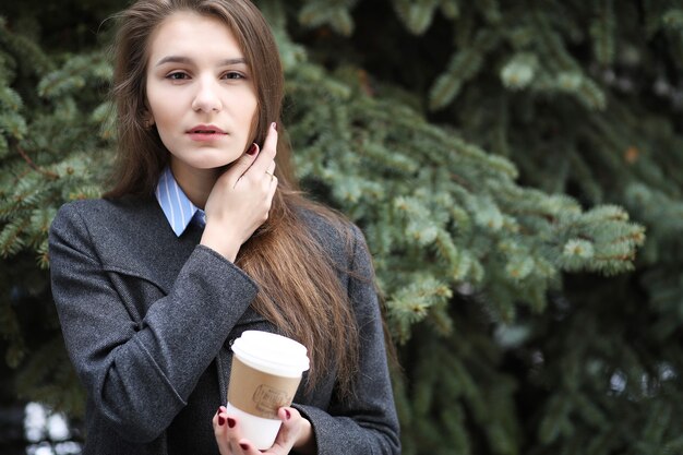 Chica joven con una taza de café de papel al aire libre