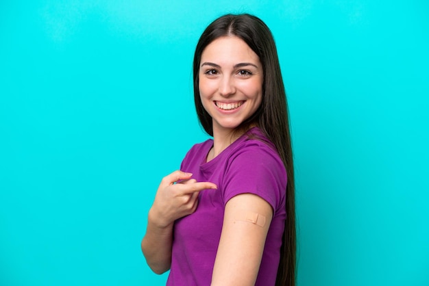 Chica joven con tiritas aislado sobre fondo azul y apuntando