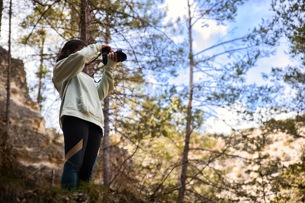 Chica joven tomando fotografías en el bosque