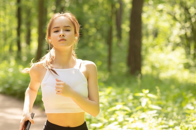 Chica joven en uniforme deportivo corre por la mañana en el parque