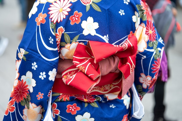 Chica joven vestida con un kimono japonés de pie frente al templo de Sensoji