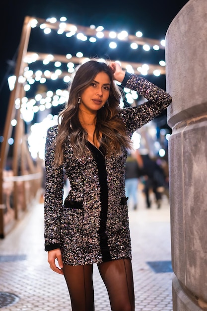 Chica joven en un vestido de moda con lentejuelas en las luces de navidad de la ciudad