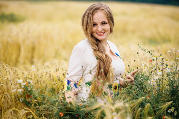 La chica joven en el vestido nacional ucraniano presentó en el campo de la guirnalda.