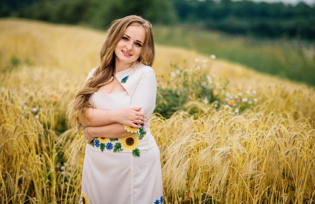 La chica joven en el vestido nacional ucraniano presentó en el campo de la guirnalda.