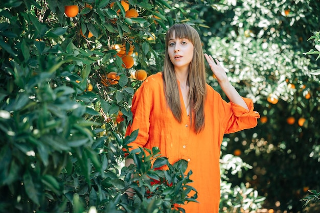 Chica joven en vestido naranja está posando para la cámara en jardín naranja