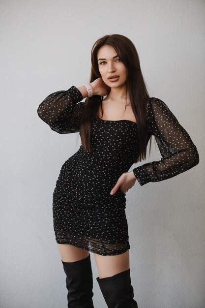 Chica joven en un vestido negro posando sobre un fondo blanco.