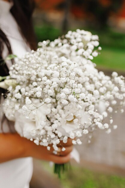 una chica joven en un vestido de novia blanco sostiene un ramo