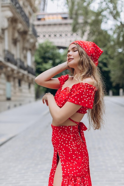 Chica joven en vestido rojo cerca de la Torre Eiffel en París en un día soleado de verano