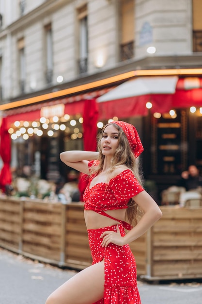 Chica joven en vestido rojo cerca de la Torre Eiffel en París en un día soleado de verano