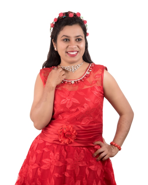 Chica joven en vestido rojo posando en la pared blanca