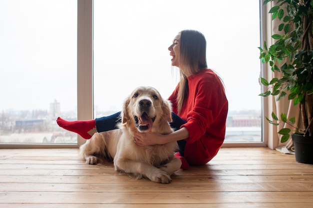 Foto chica juega con golden retriever de raza de perro en casa en el piso mujer con una mascota juntos yace en el piso