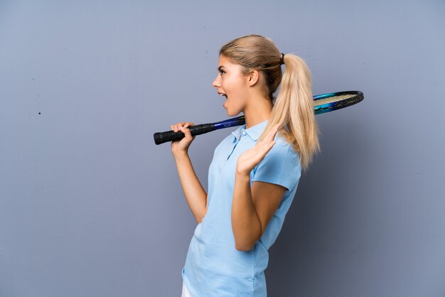 Chica de jugador de tenis adolescente sobre pared gris con expresión facial sorpresa