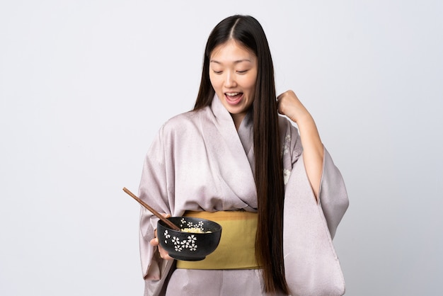 Chica en kimono sosteniendo un plato de fideos