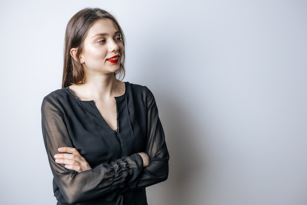 Chica con labios rojos y una blusa negra cruza sus manos