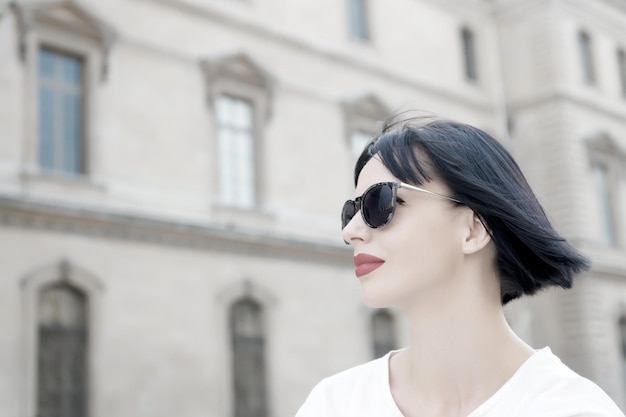 Chica con labios rojos en pose de gafas de sol en la calle de la ciudad