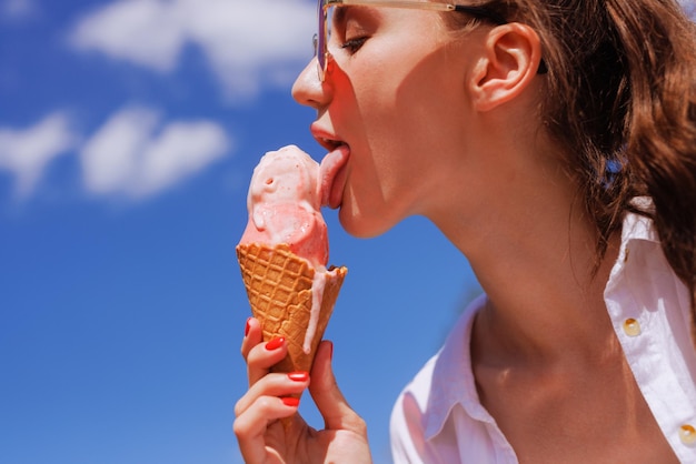 Chica lame helado en un primer plano de cono en verano caluroso