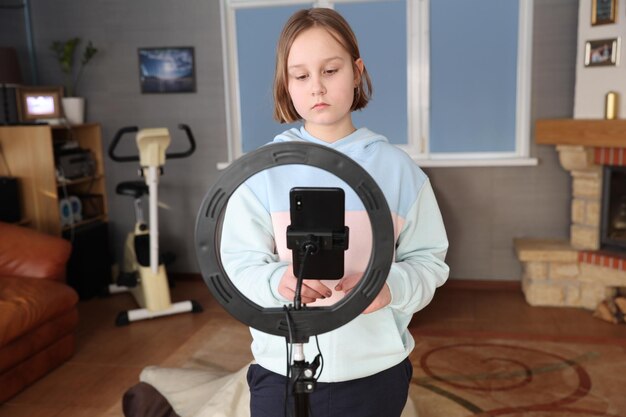 Chica con una lámpara de anillo para la educación a distancia de un teléfono inteligente