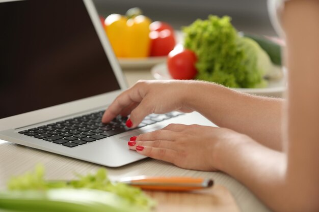 Chica con laptop en cocina Concepto de blogger de comida