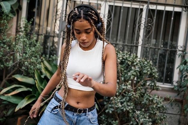 chica con largas trenzas rubias bailando en la calle mientras sonríe y disfruta