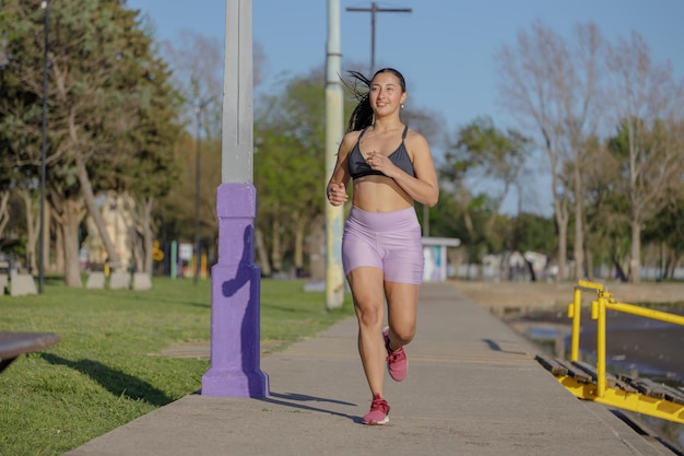 Una chica latina corriendo en un parque público.