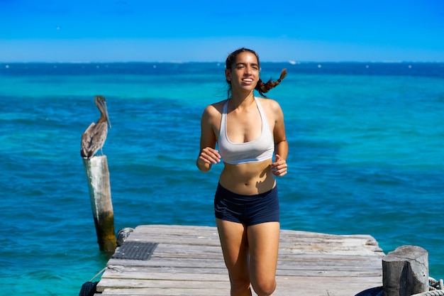 Chica latina corriendo en la playa del muelle caribeño
