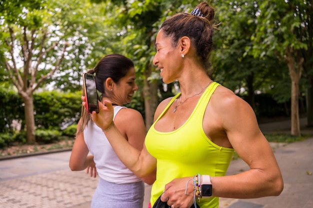 Chica latina haciendo deporte en un parque en el estilo de vida de la ciudad una vida sana dos chicas muy felices tomando fotos después de terminar el ejercicio