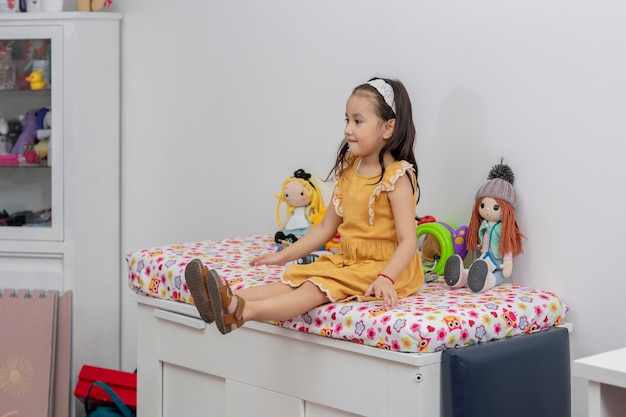 Chica latina sentada en una cama en un consultorio pediátrico esperando al pediatra