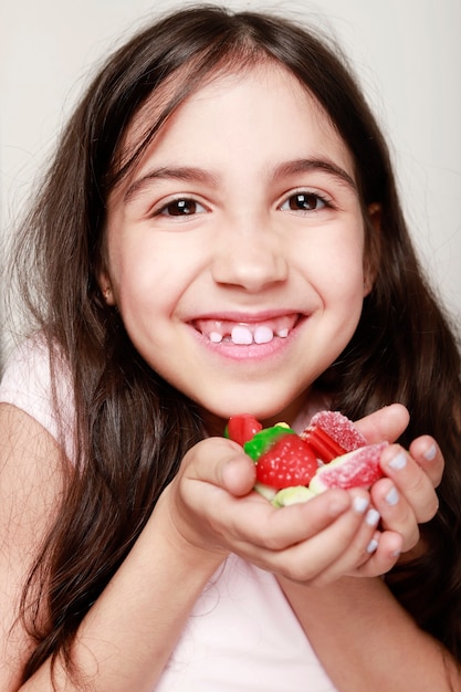 Foto chica latina sonriendo a la cámara con una gran cantidad de caramelos en sus manos