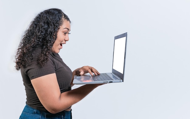 Foto chica latina sorprendida mirando una promoción en la pantalla de una computadora portátil aislada mujer latina sorprendida usando una computadora portátil aislada