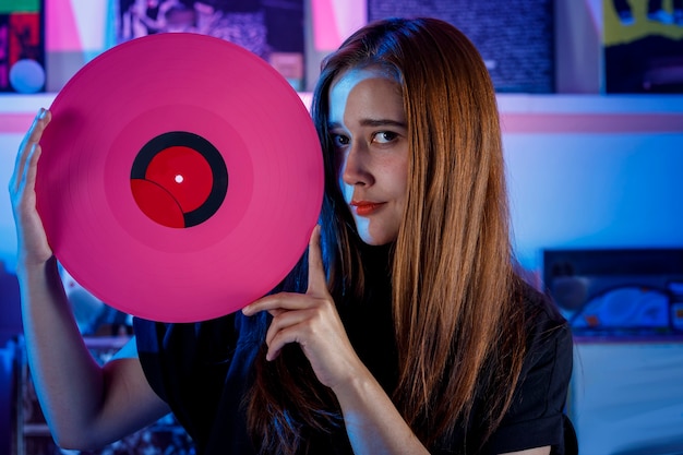 Chica latina sosteniendo un disco de vinilo en sus manos Concepto de chica dj en tienda de discos