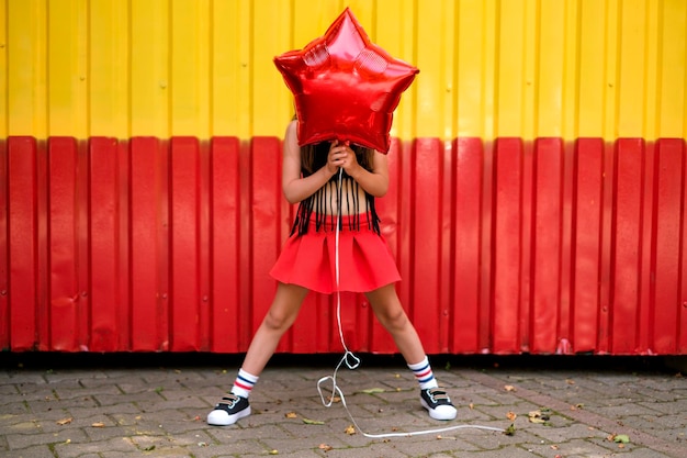 Chica en leggins y zapatillas cubre la cara con globo.