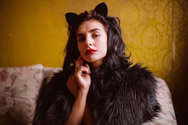 Chica en lencería y un abrigo negro con cabello negro rizado posando en una foto vintage interior vintage