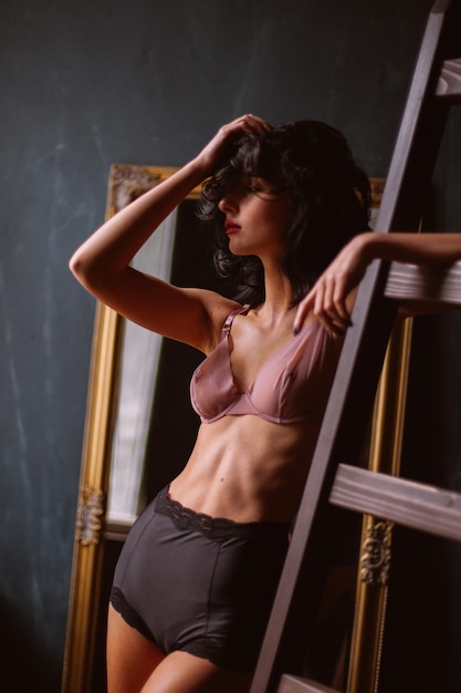 Chica en lencería sexy con cabello negro rizado posando en interior vintage procesamiento de fotos vintage