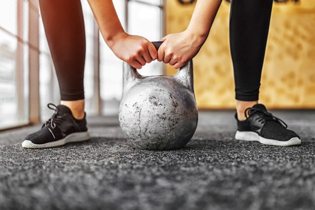 Chica levantando kettlebell desde el suelo en el gimnasio